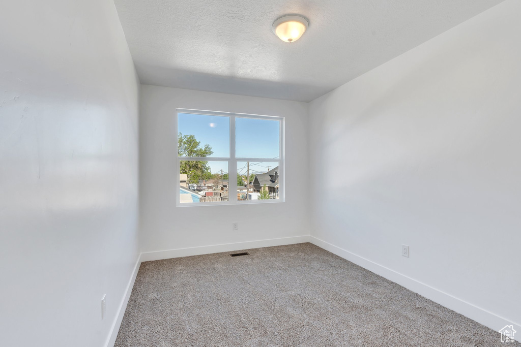Carpeted empty room with baseboards and a textured ceiling