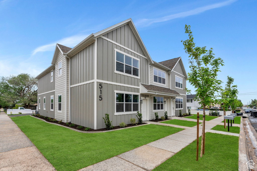 View of front of house featuring board and batten siding, a front lawn, and roof with shingles