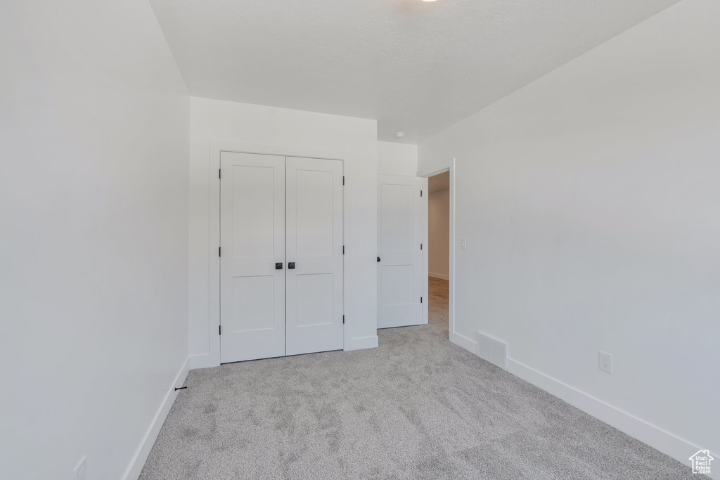 Unfurnished bedroom with carpet, baseboards, and a closet