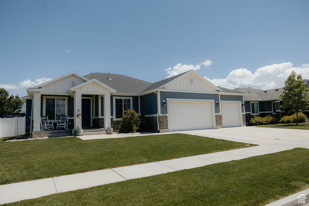 View of front of property featuring board and batten siding, an attached garage, driveway, and a front yard