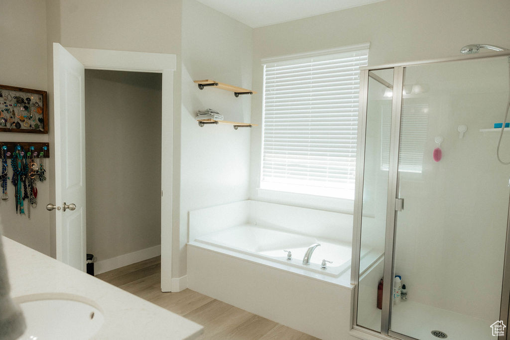 Bathroom featuring wood finished floors, a stall shower, and a garden tub