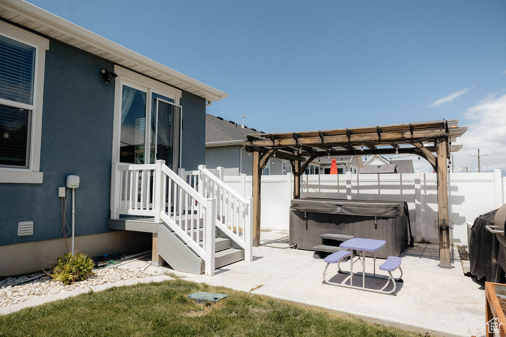 Fenced backyard with a hot tub, a patio area, and a pergola