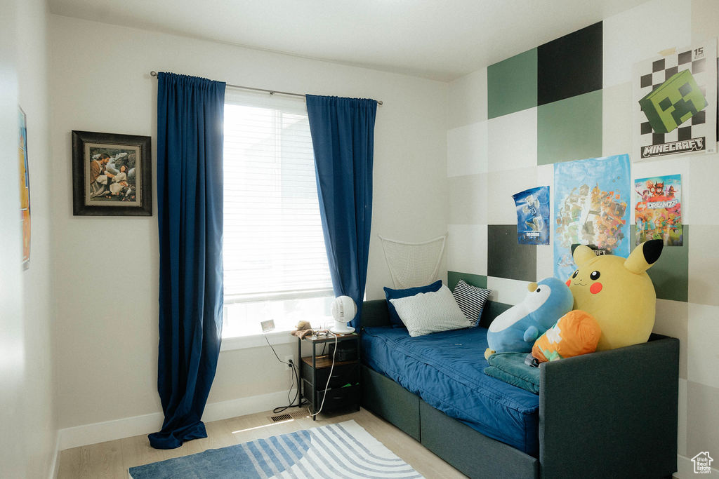 Bedroom with multiple windows, wood finished floors, and baseboards