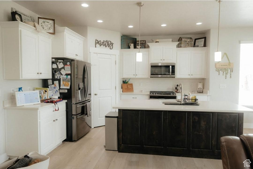 Kitchen featuring appliances with stainless steel finishes, a sink, light countertops, white cabinetry, and recessed lighting