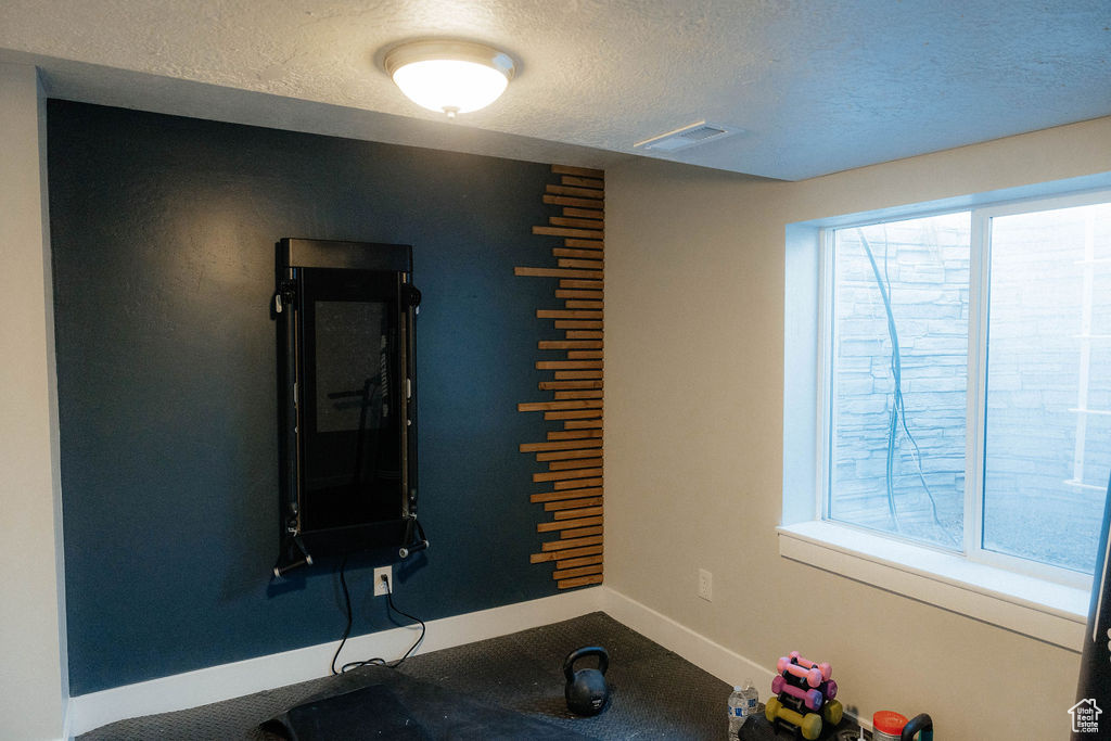 Exercise room with a textured ceiling and baseboards