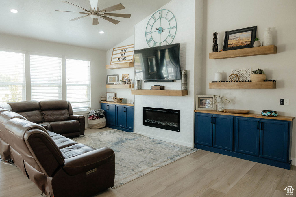 Living area featuring ceiling fan, light wood finished floors, vaulted ceiling, a fireplace, and recessed lighting