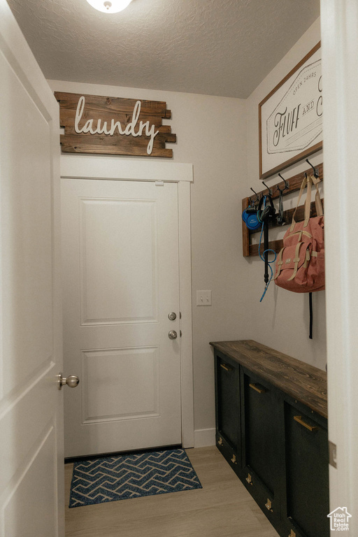 Mudroom featuring light wood finished floors and a textured ceiling