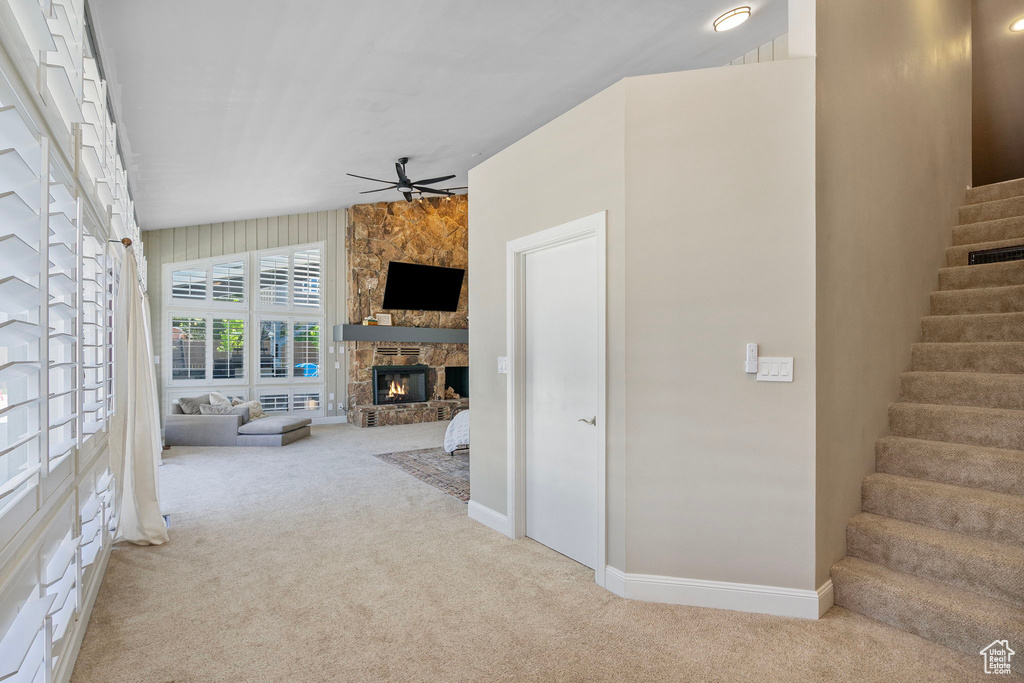 Unfurnished living room with carpet flooring, ceiling fan, stairs, a fireplace, and baseboards