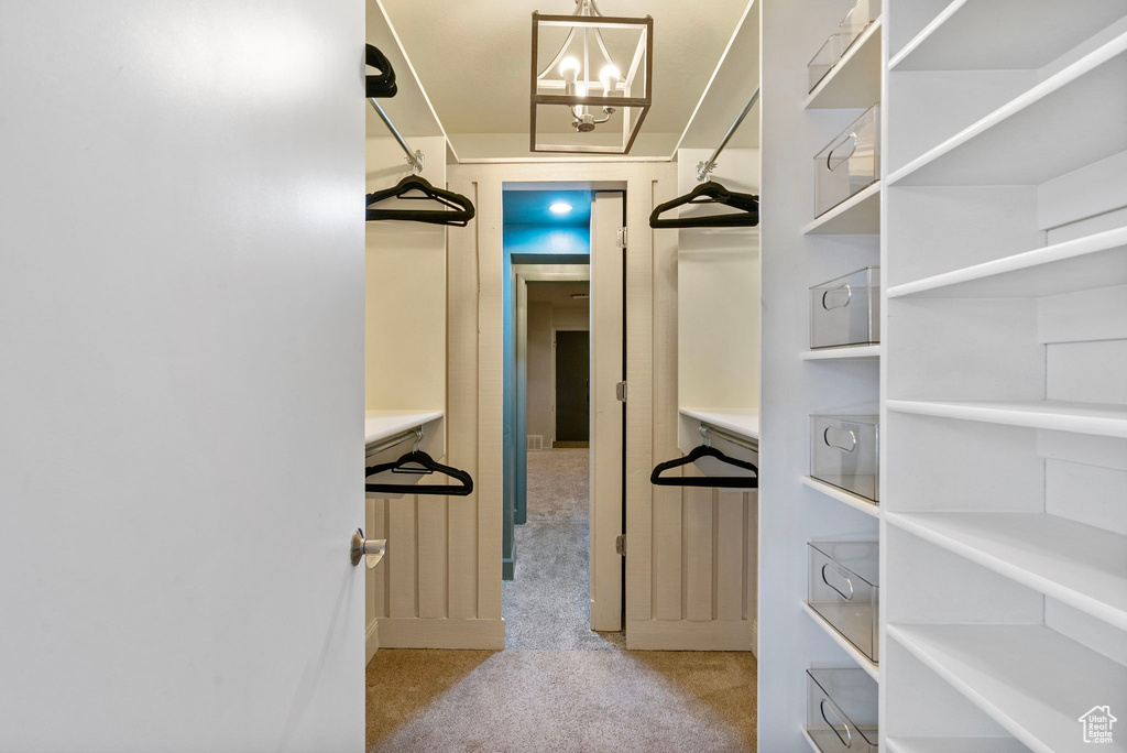 Spacious closet featuring carpet and a chandelier