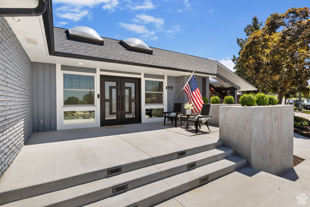 Entrance to property featuring covered porch and roof with shingles