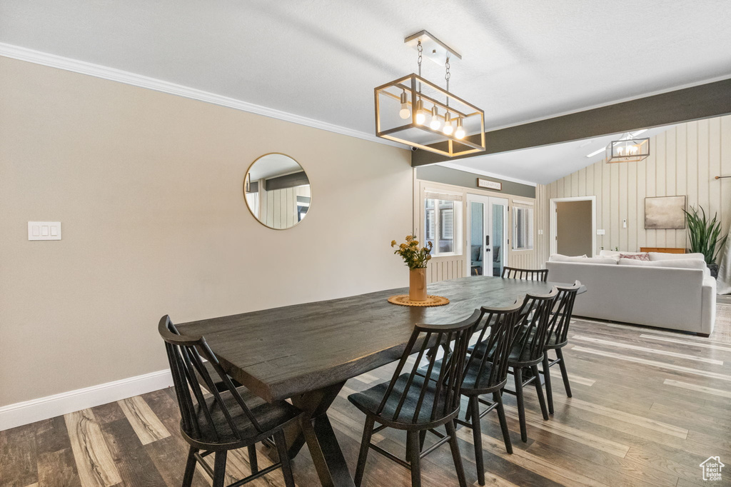 Dining space with ornamental molding, wood finished floors, baseboards, a chandelier, and french doors