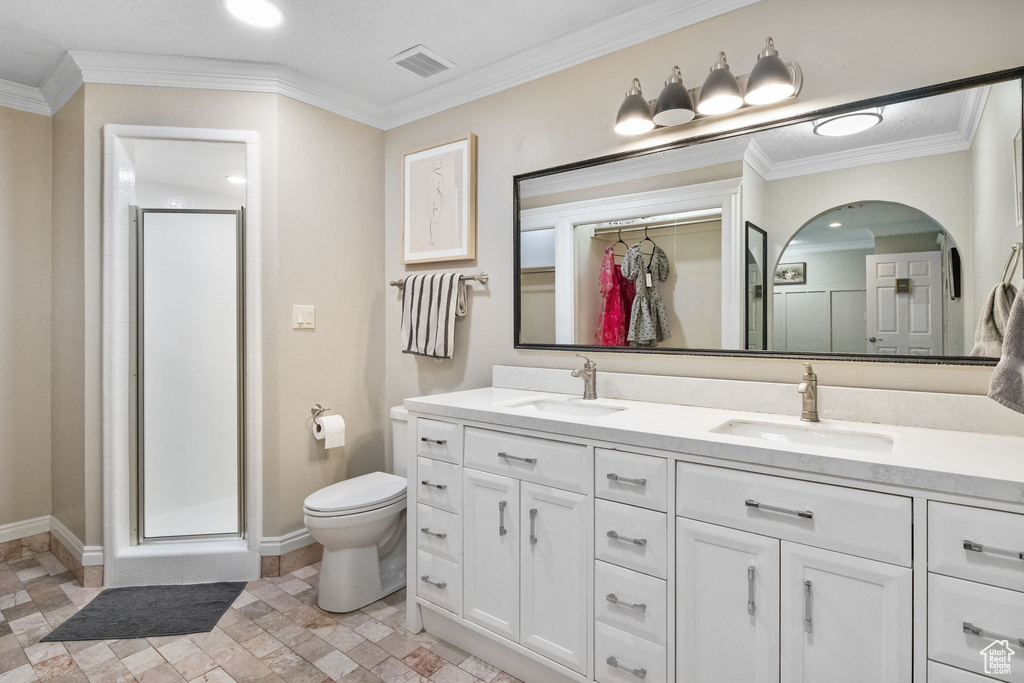 Bathroom featuring double vanity, toilet, a stall shower, baseboards, and a spacious closet