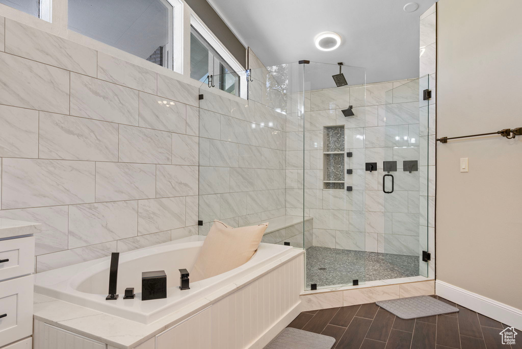 Full bathroom featuring a shower stall, a garden tub, wood tiled floors, and baseboards