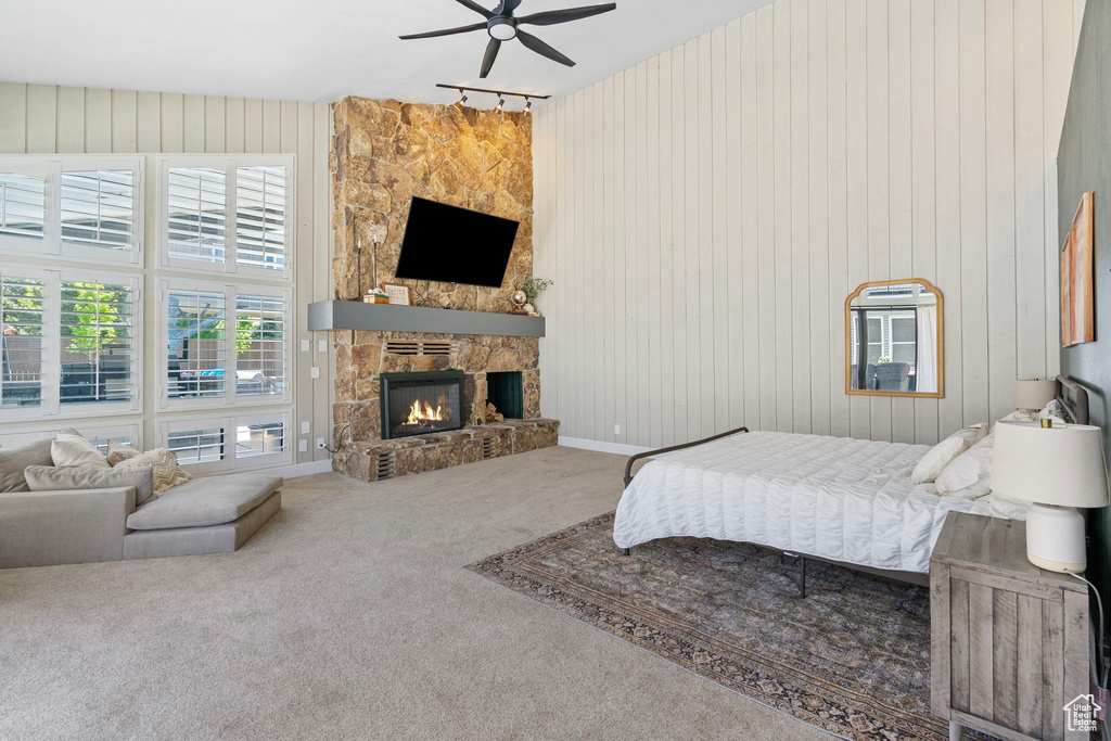 Carpeted bedroom with a stone fireplace and wooden walls