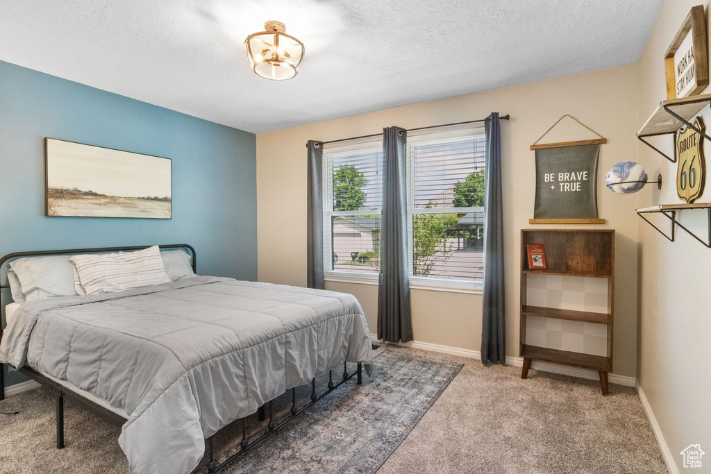 Carpeted bedroom featuring baseboards and a textured ceiling