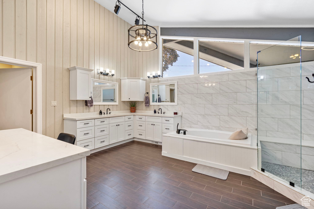 Bathroom with double vanity, a garden tub, a chandelier, lofted ceiling, and a shower stall