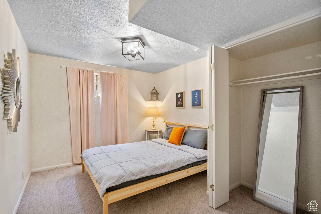 Bedroom with carpet flooring, baseboards, and a textured ceiling