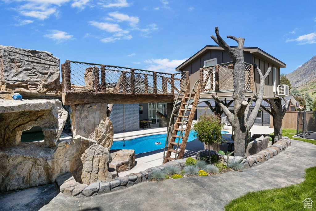 Rear view of house with a patio area, an outdoor pool, board and batten siding, and stairway