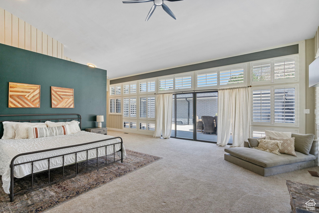 Carpeted bedroom with access to exterior, ceiling fan, and a high ceiling