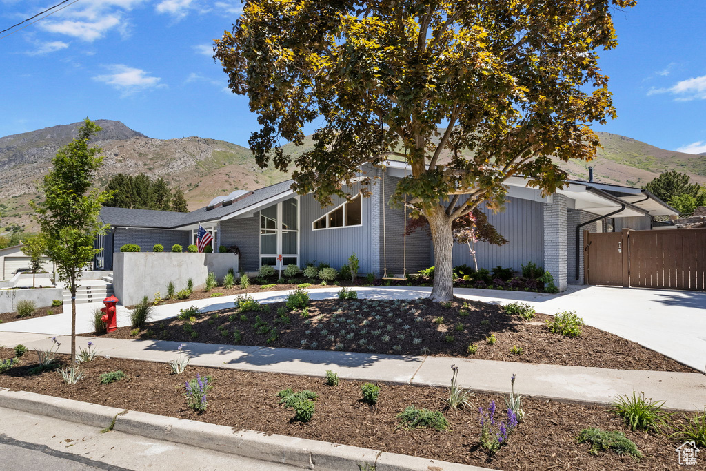 Mid-century inspired home featuring curved driveway, a mountain view, brick siding, and a gate