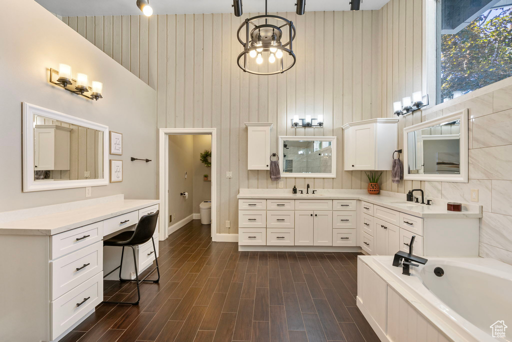Bathroom featuring vanity, a bath, toilet, wood finished floors, and baseboards