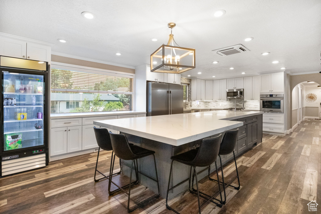 Kitchen featuring appliances with stainless steel finishes, crown molding, white cabinetry, arched walkways, and recessed lighting