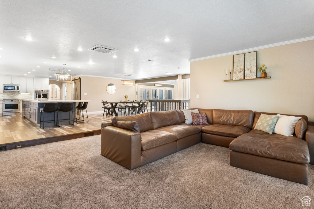 Living area with crown molding, recessed lighting, and light colored carpet