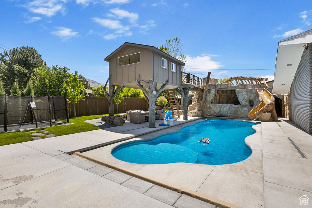 View of swimming pool featuring a patio area, a fenced backyard, an outdoor living space, and a water slide