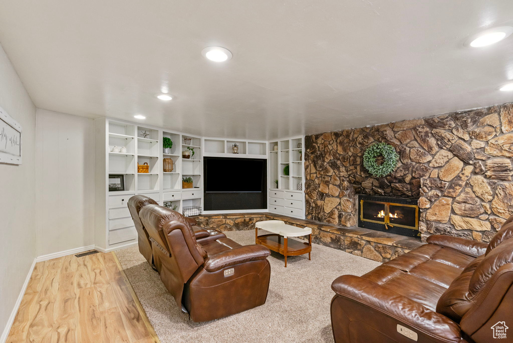 Living area with wood finished floors, baseboards, recessed lighting, and a stone fireplace