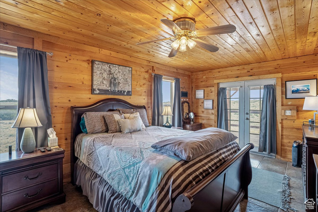 Bedroom featuring multiple windows, access to outside, wooden ceiling, wood walls, and french doors