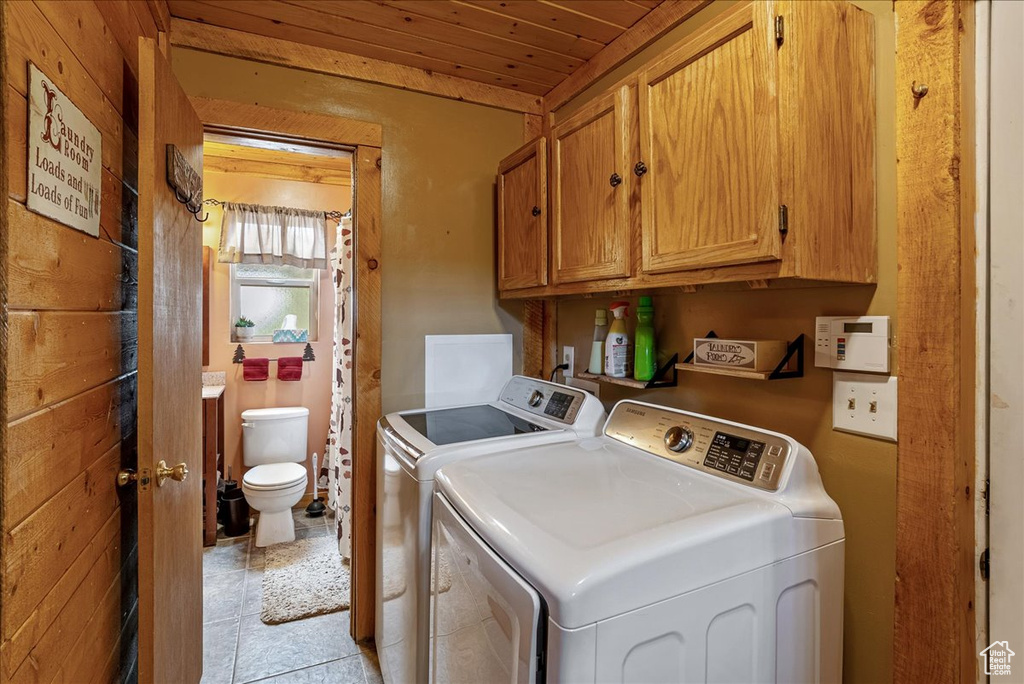 Clothes washing area with washer and dryer, cabinet space, and wooden ceiling