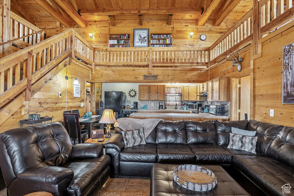 Living area with wood walls, wooden ceiling, beamed ceiling, a towering ceiling, and tile patterned floors