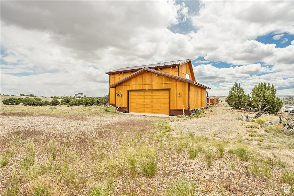 View of side of property with driveway, a garage, and an outbuilding