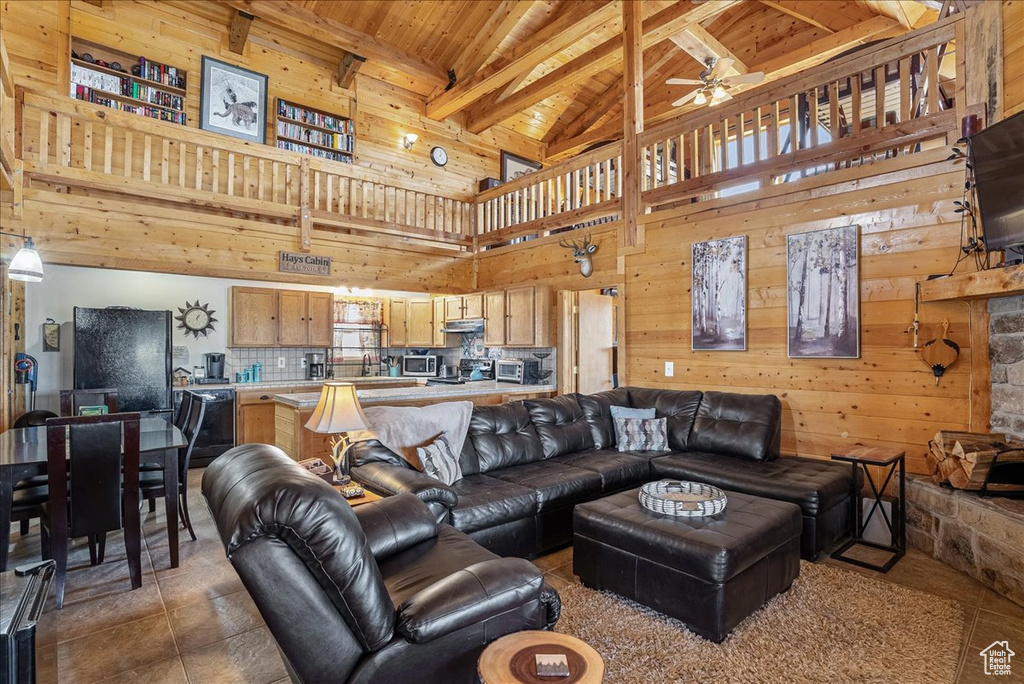 Living area featuring high vaulted ceiling, ceiling fan, wooden ceiling, beam ceiling, and wood walls