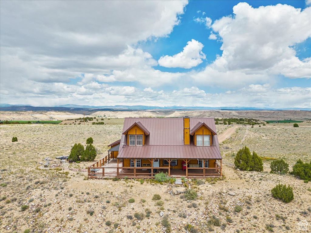 Chalet / cabin with covered porch, a view of rural / pastoral area, metal roof, and a mountain view
