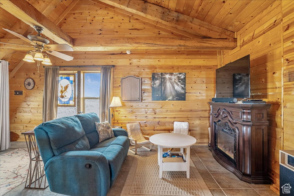 Living room with wood walls, wooden ceiling, a ceiling fan, and a glass covered fireplace