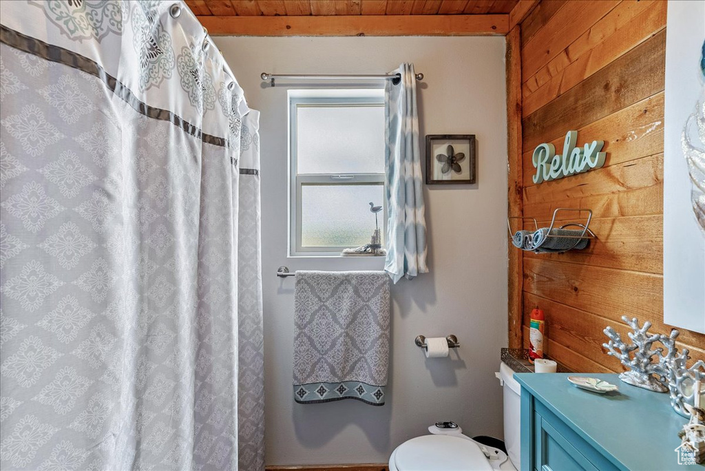 Bathroom with wood walls, wood ceiling, toilet, vanity, and a shower with shower curtain