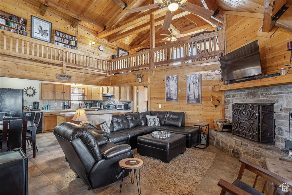 Living room featuring ceiling fan, wood walls, wood ceiling, high vaulted ceiling, and beam ceiling
