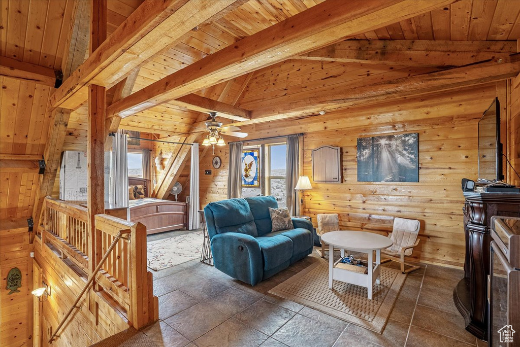 Living room with wooden walls, plenty of natural light, wooden ceiling, and a ceiling fan