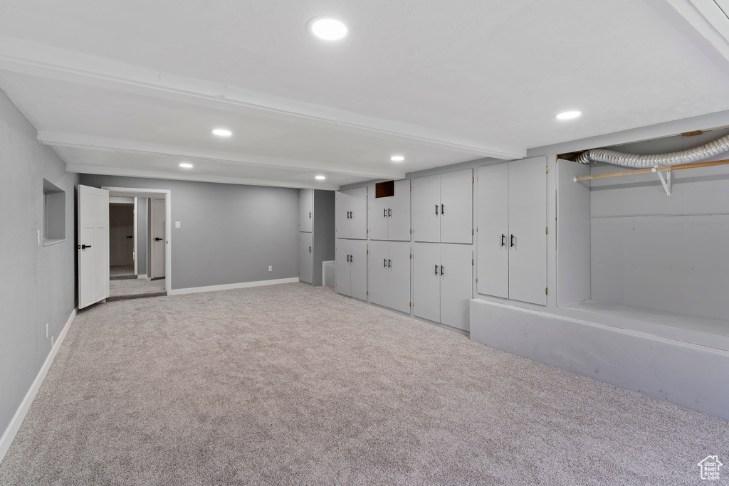 Finished below grade area featuring light colored carpet, recessed lighting, and baseboards
