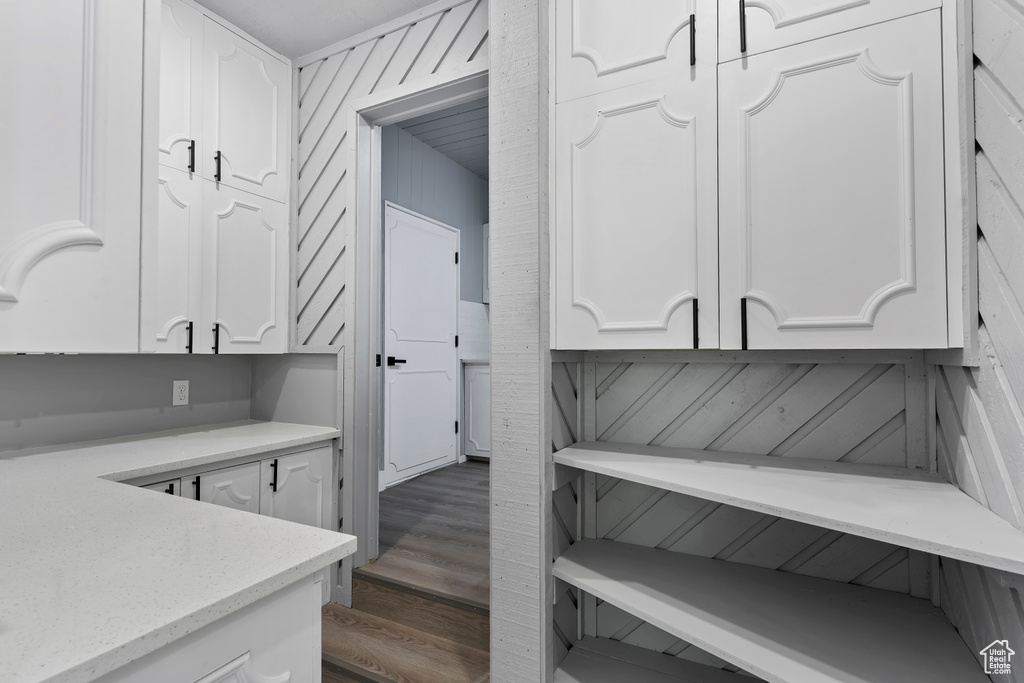 Interior space with white cabinetry, light stone countertops, and wood finished floors
