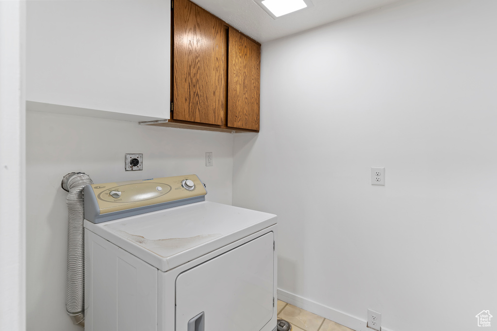 Laundry room featuring washer / clothes dryer, cabinet space, baseboards, and light tile patterned floors