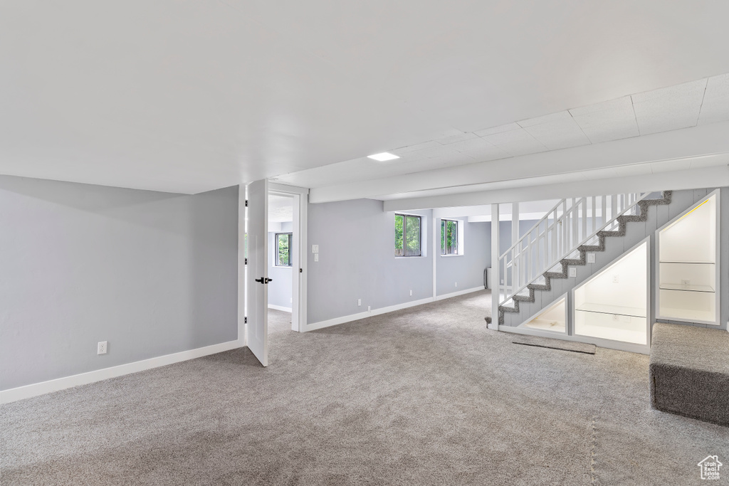 Basement with stairs, baseboards, and carpet flooring