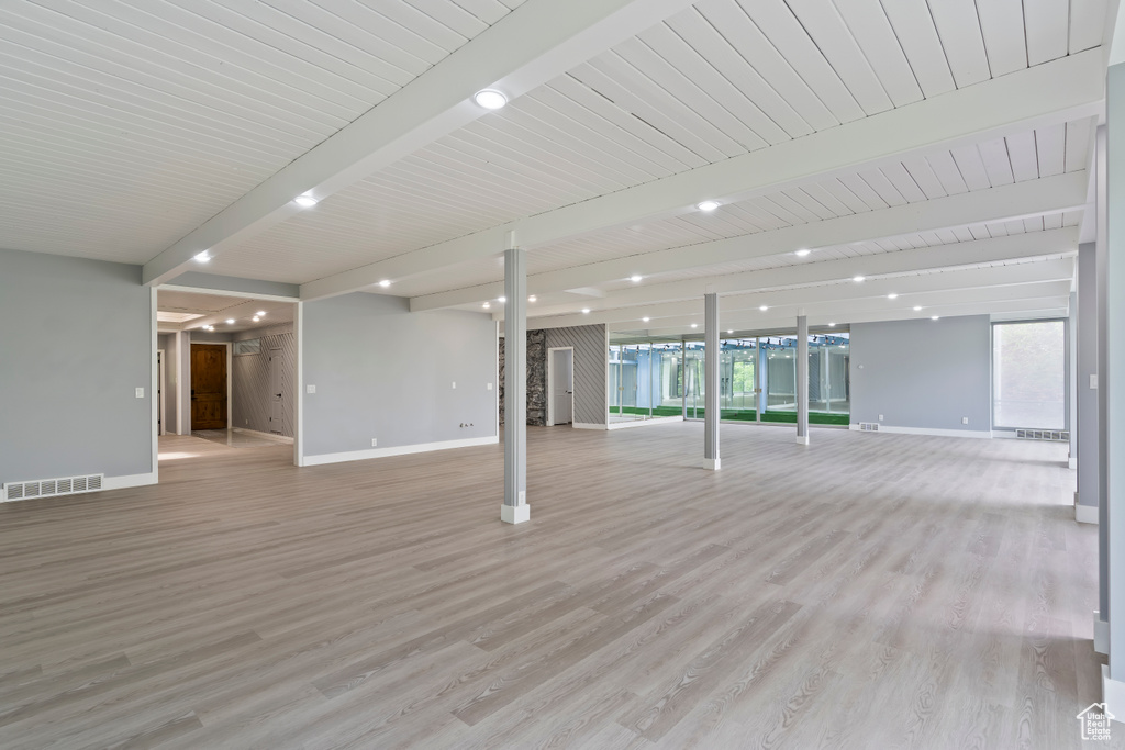 Interior space with beamed ceiling, baseboards, light wood-type flooring, and healthy amount of natural light