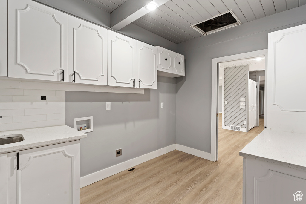 Washroom featuring washer hookup, light wood finished floors, baseboards, cabinet space, and wooden ceiling
