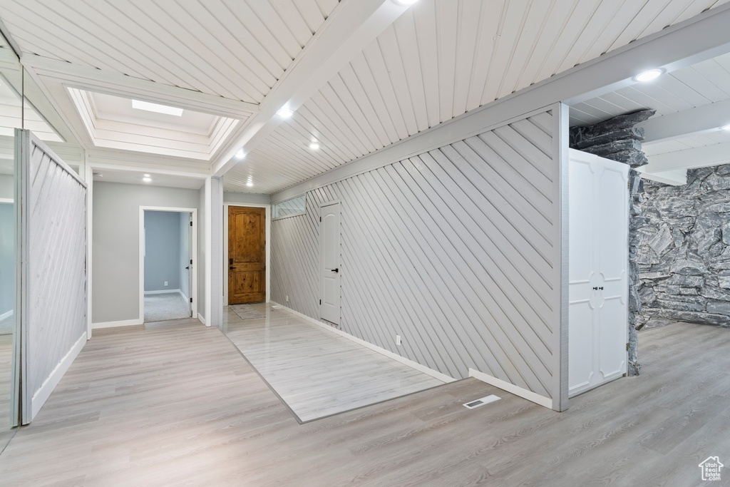 Unfurnished bedroom with baseboards, light wood finished floors, and beamed ceiling