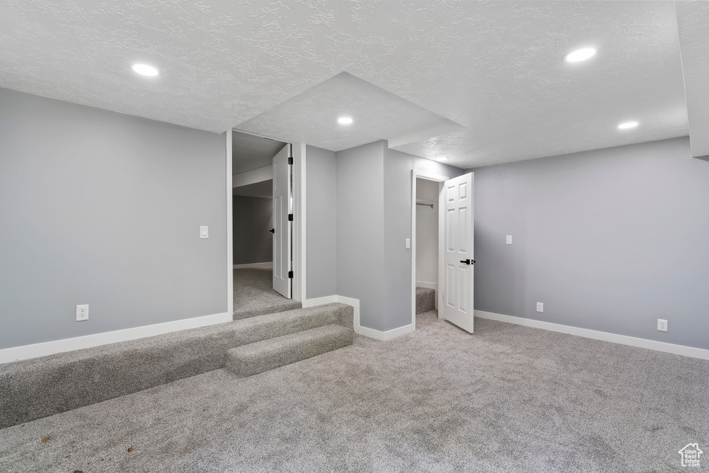 Finished below grade area featuring carpet floors, recessed lighting, baseboards, and a textured ceiling