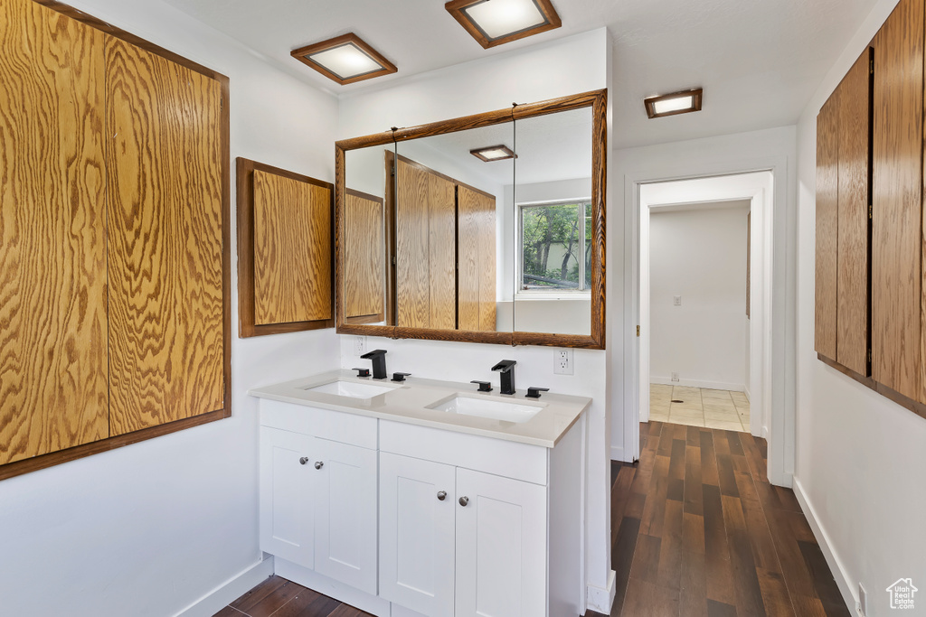 Full bathroom featuring double vanity, wood finished floors, and baseboards