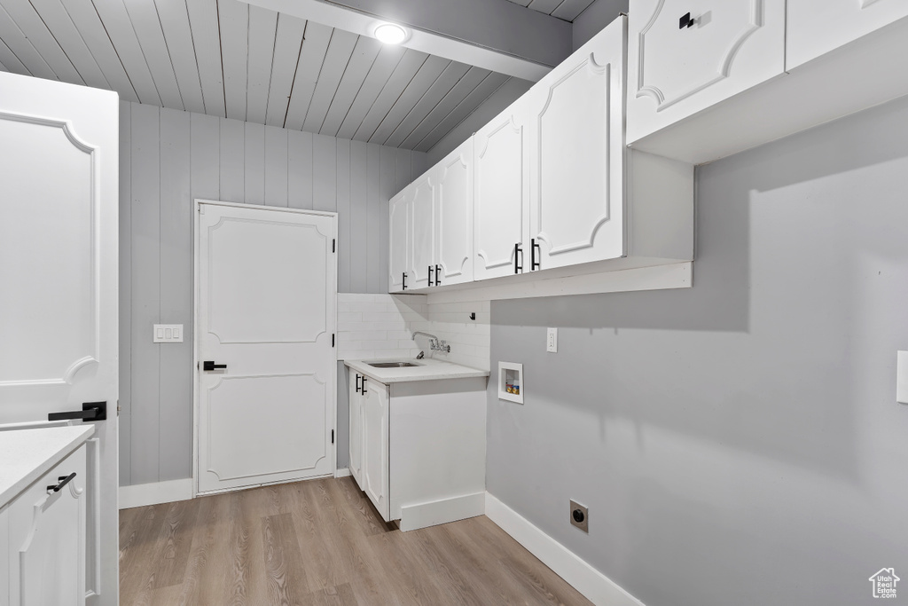 Laundry area featuring washer hookup, light wood finished floors, electric dryer hookup, cabinet space, and baseboards