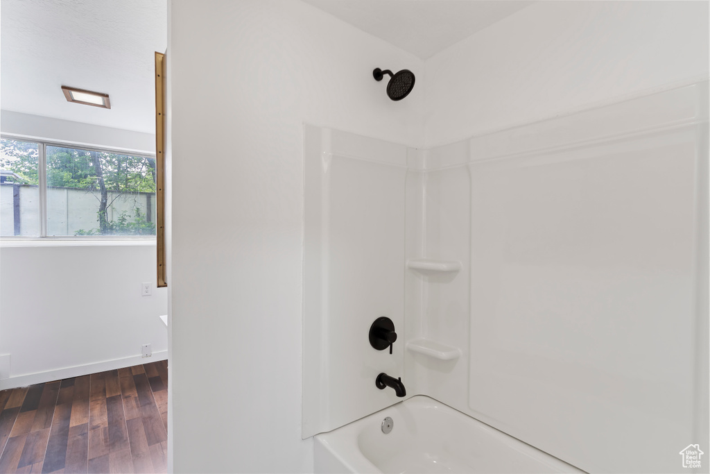 Bathroom featuring tub / shower combination, wood finished floors, and baseboards